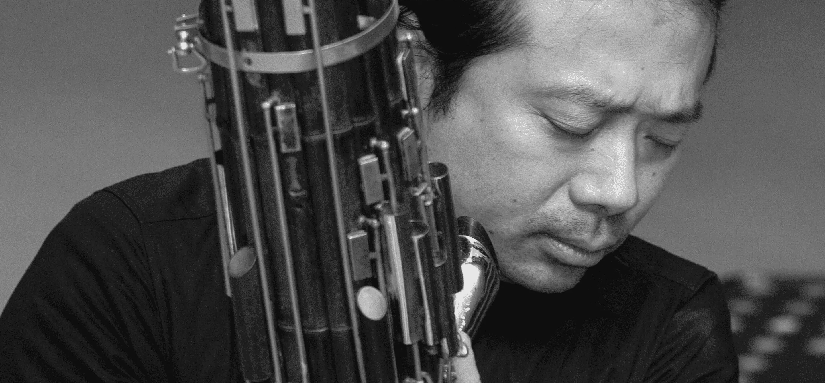 O músico Wu Wei segura o sheng, seu instrumento. A imagem é em preto e branco.