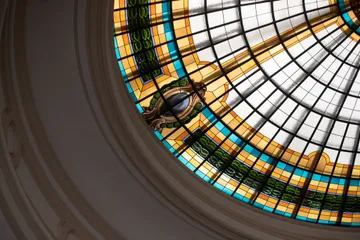 O vitral do teto da Sala São Paulo tem as cores amarelo e azul. A luz do sol está batendo nos vitrais. 