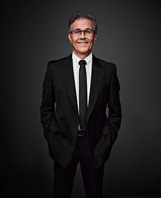 Laércio Resende é um homem branco, na faixa dos 50 anos, com cabelos curtos grisalhos. Ele veste camisa branca, gravata e terno pretos, e usa óculos. Ele sorri para a foto.