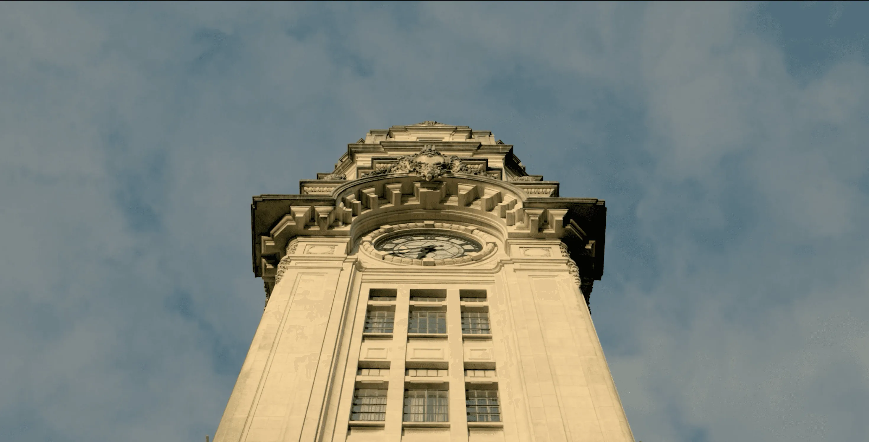 A foto mostra a torre do relógio da Sala São Paulo e um céu azul.  
