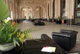 Imagem ampla do Hall Principal, com poltronas, sofás e uma planta.