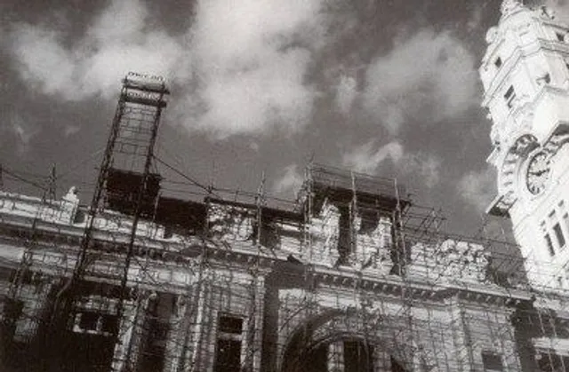A foto em preto e branco mostra a restauração da fachada da Sala São Paulo. É possível ver uma grande estrutura de praticáveis em frente as janelas da Sala. 