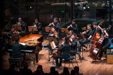 Os músicos da Academia da Osesp estão tocando seus instrumentos no palco do Teatro B32.