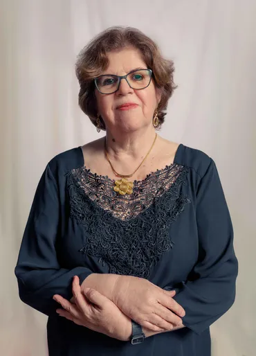 Maria Emilia Moura é uma senhora branca, de cabelos castanhos e óculos.