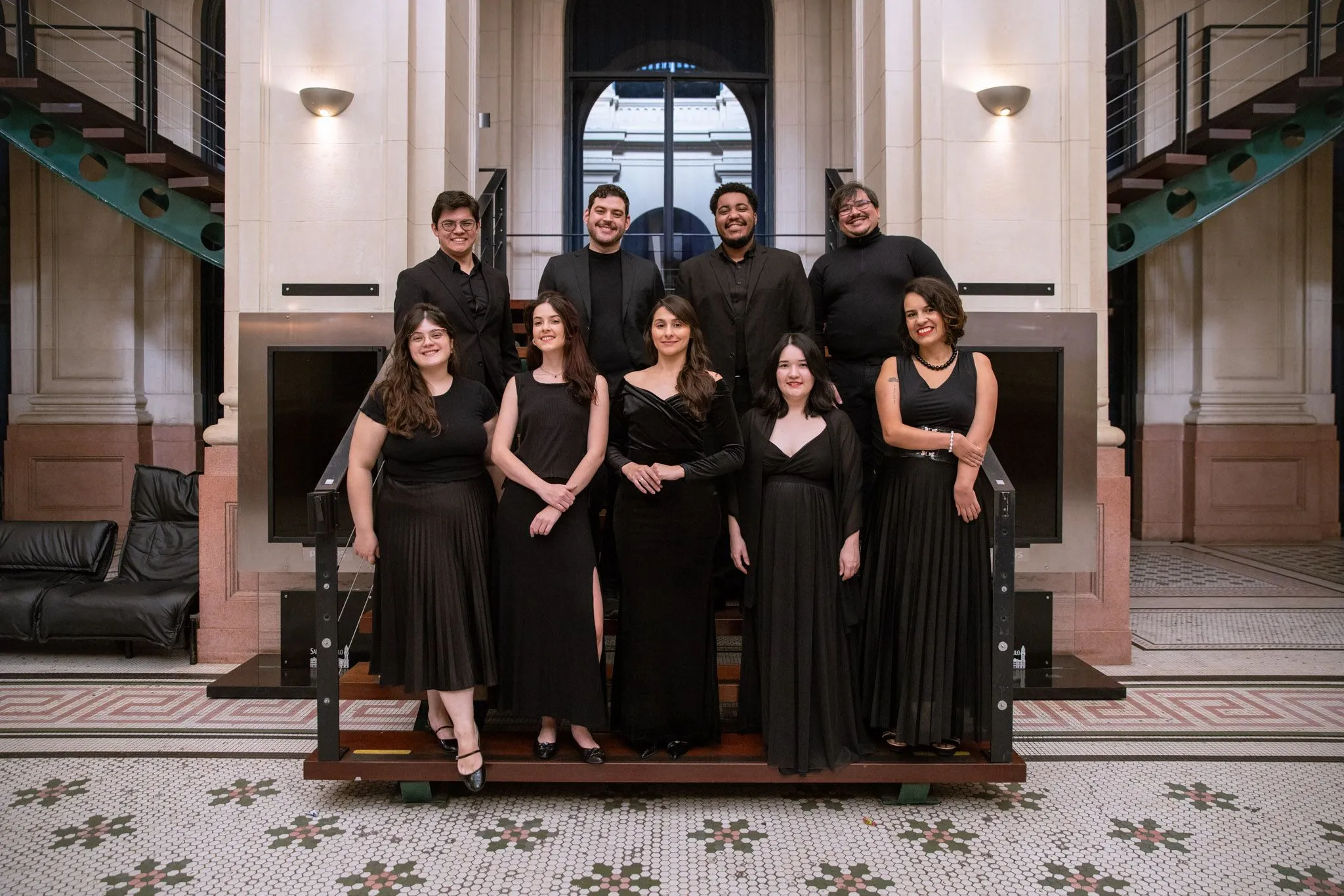 Foto dos formandos da classe de canto vestidos de preto na escada do foyer da Sala São Paulo.