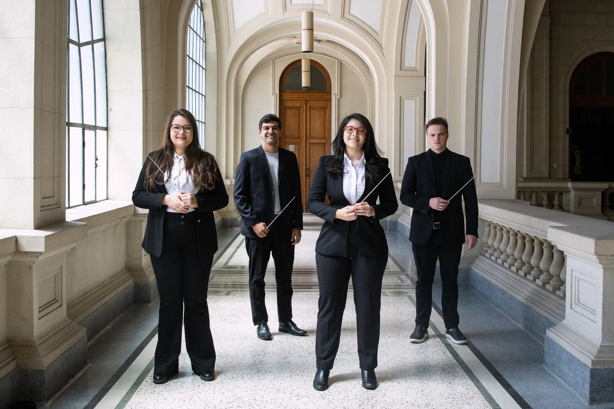 The four students from the Academy are in the São Paulo Hall. They are all men and holding their batons.