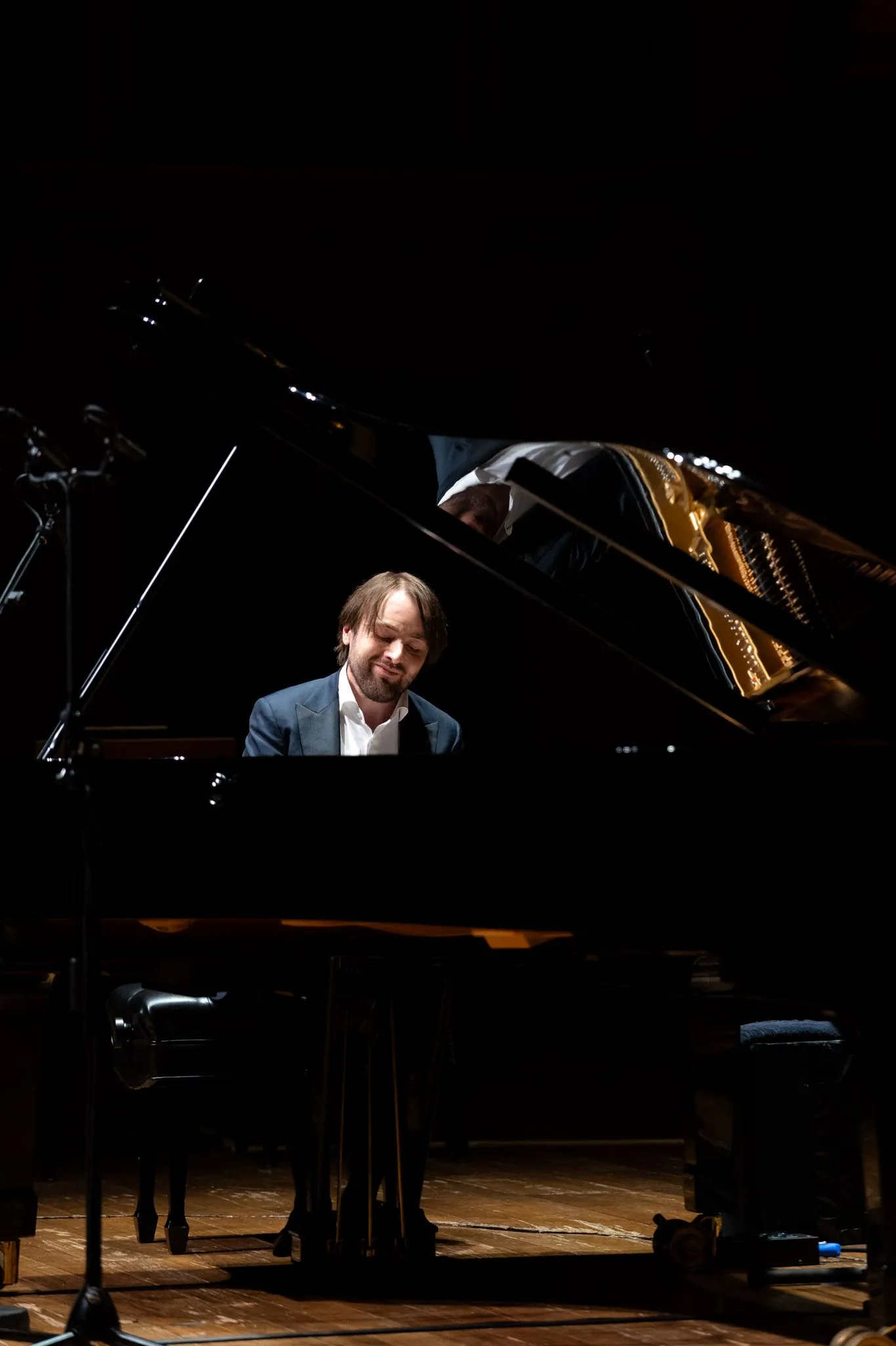Daniil Trifonov, homem branco de cabelo e barba castanhos, sorrindo e tocando piano