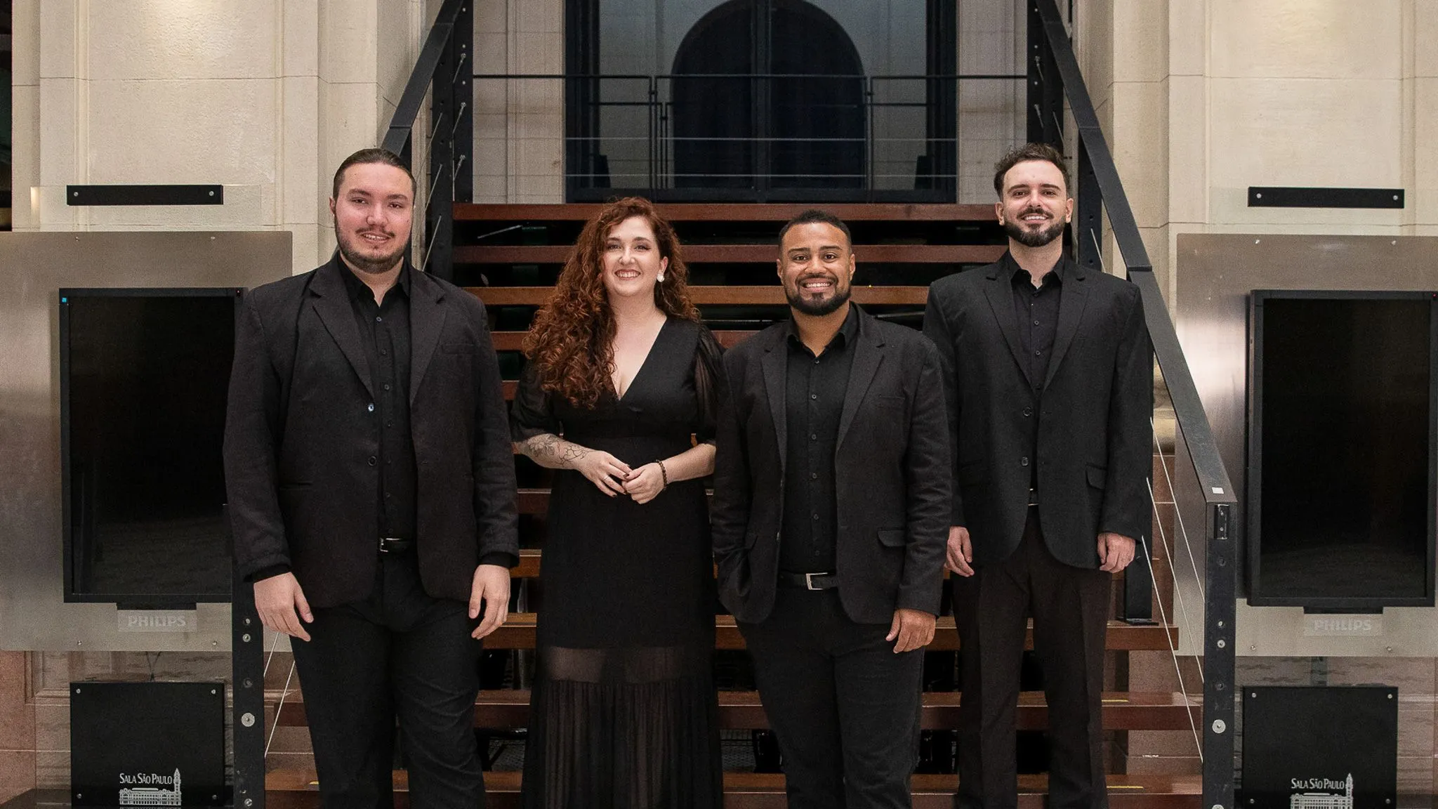 Foto de quatro cantores na escada da Sala São Paulo