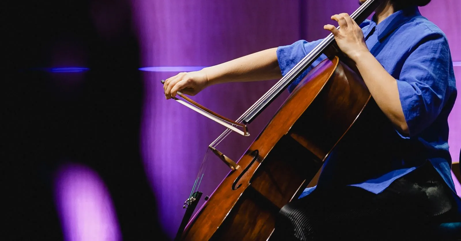 A imagem mostra uma mulher tocando violoncelo.