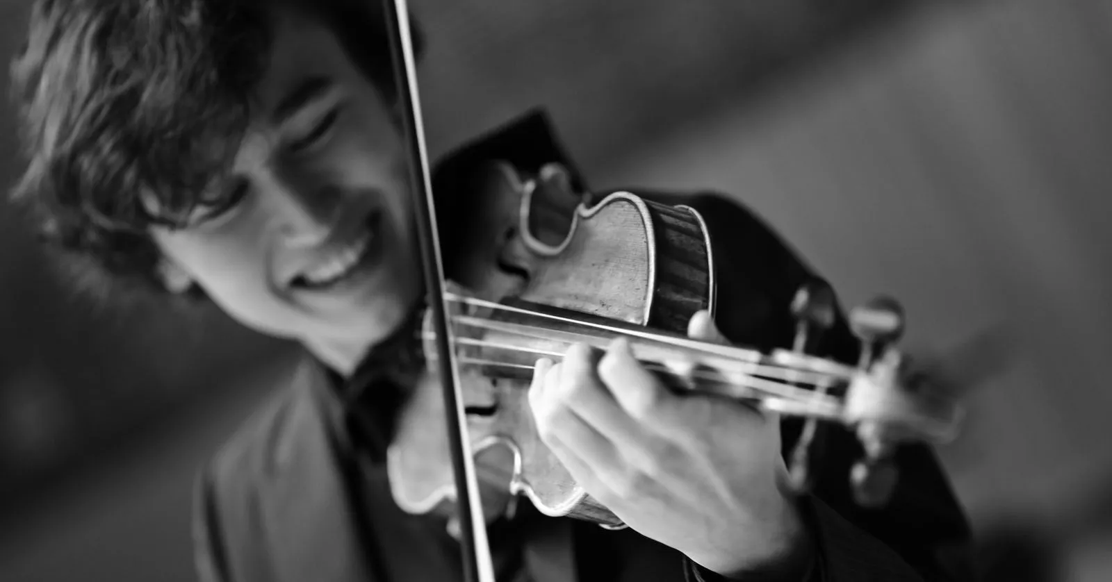Daniel Lozakovich é um homem branco, de cabelos pretos. Ele está tocando violino.