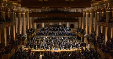A imagem mostra a Orquestra e o Coro no palco da Sala São Paulo.