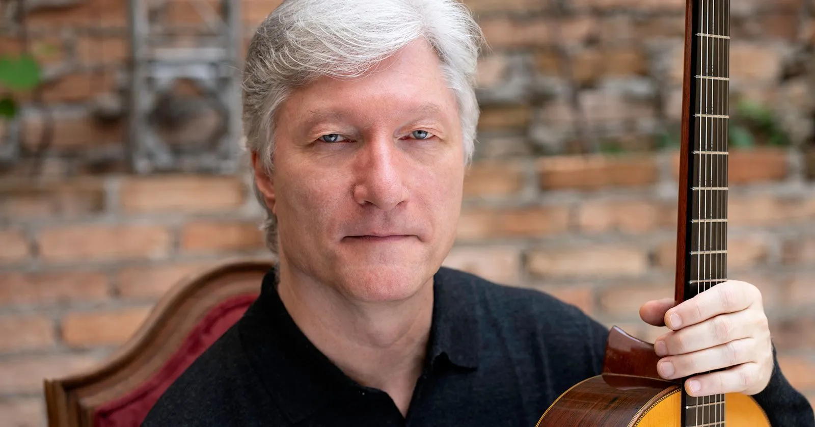 Fabio Zanon é um homem branco, de cabelos loiros. Ele segura um violão.