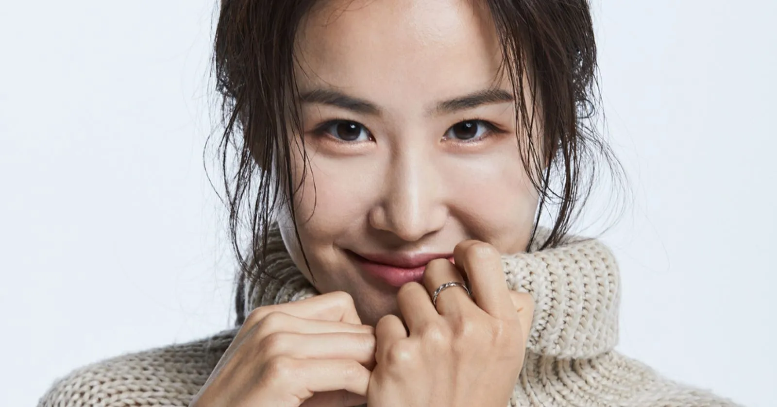 Hera Park é uma mulher asiática, de cabelos castanhos. Ela usa um vestido preto tomara que caia.