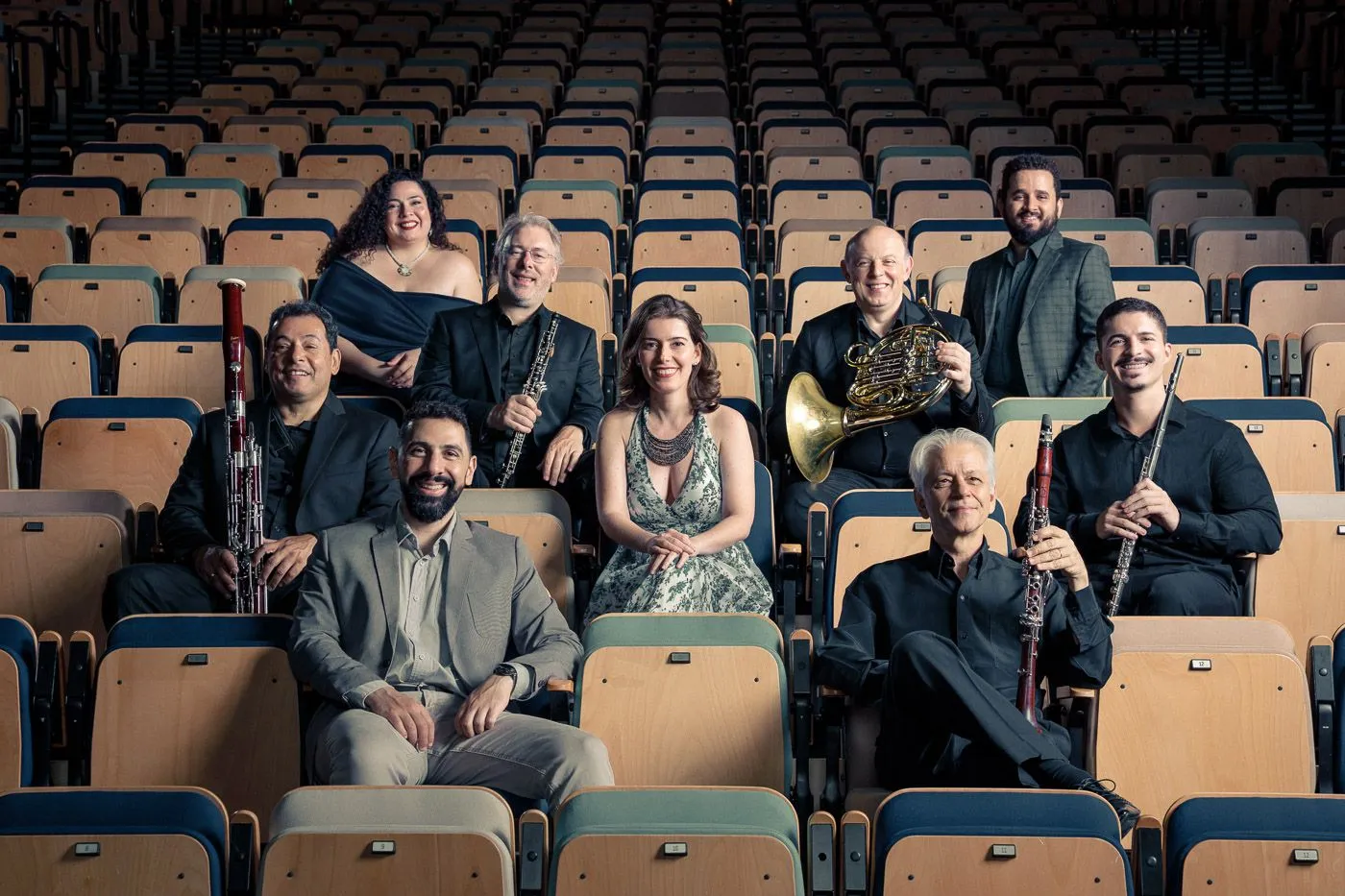A imagem mostra os músicos que tocarão neste recital sentados na arquibancada da Estação Motiva Cultural.