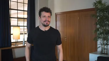 Paolo Bortolameolli é um homem branco, de cabelos e barba castanhos. Ele usa camiseta preta e sorri.