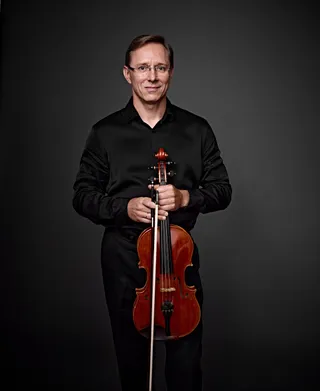Vladimir Klementiev is a white man with light brown hair, wearing glasses and a black shirt.